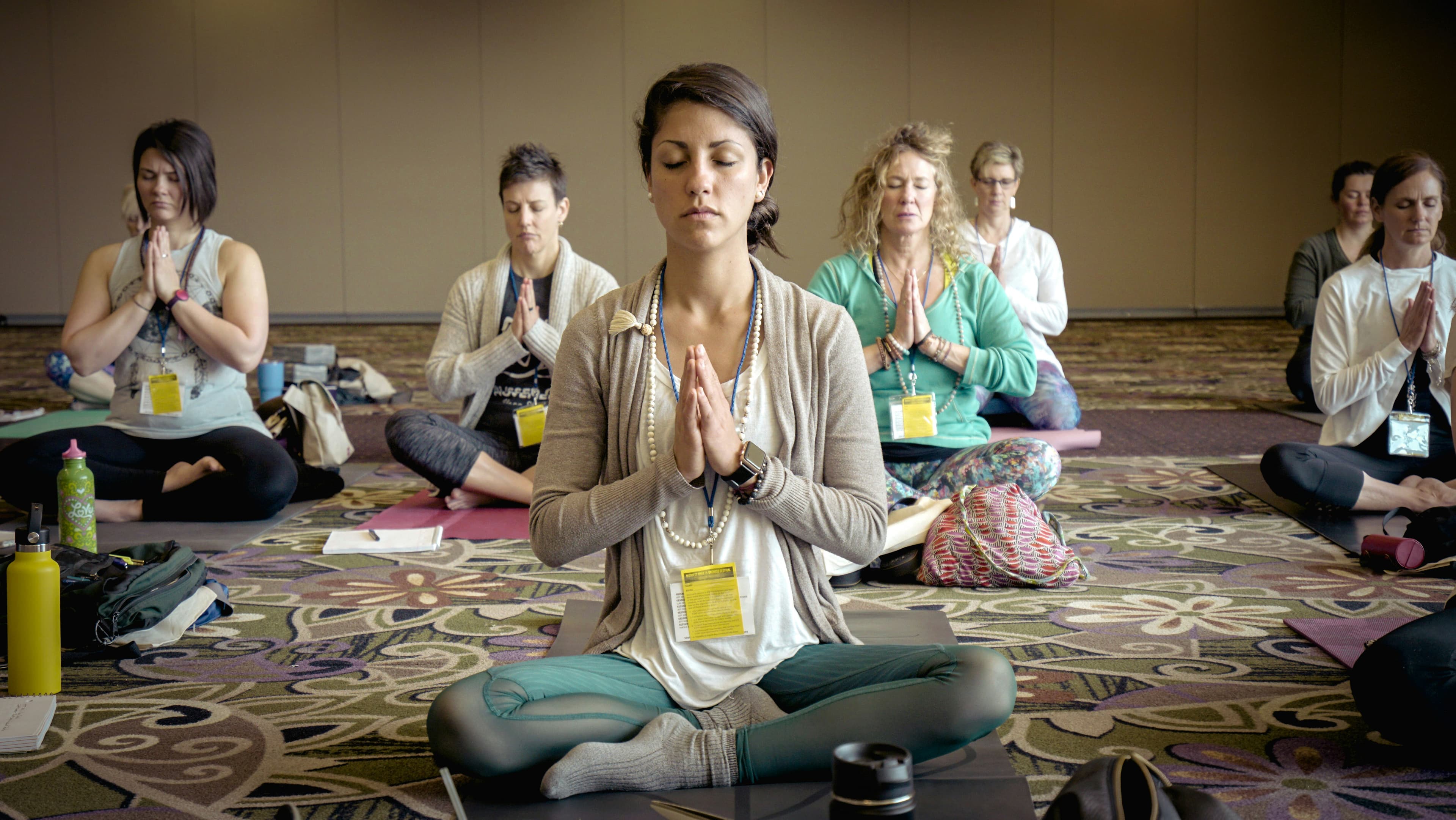 A corporate group in a seated meditation pose during an office yoga session